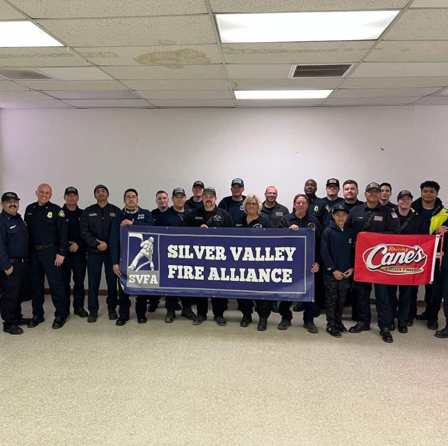 A Group Of Volunteer Firefighters Holding The Silver Valley Fire Alliance Sign.